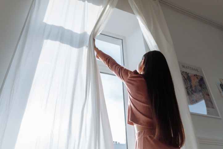 woman opens curtain